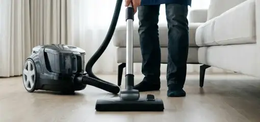 Professional house cleaner vacuuming a living room floor with a canister vacuum cleaner, Irvine, CA.