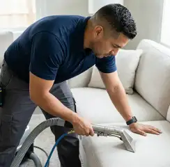 Professional upholstery cleaning technician using an extraction wand to deep-clean a fabric sofa, Irvine, CA.