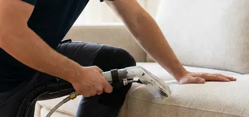 Professional upholstery cleaner deep-cleaning a fabric sofa with a handheld extraction tool, Irvine, CA.